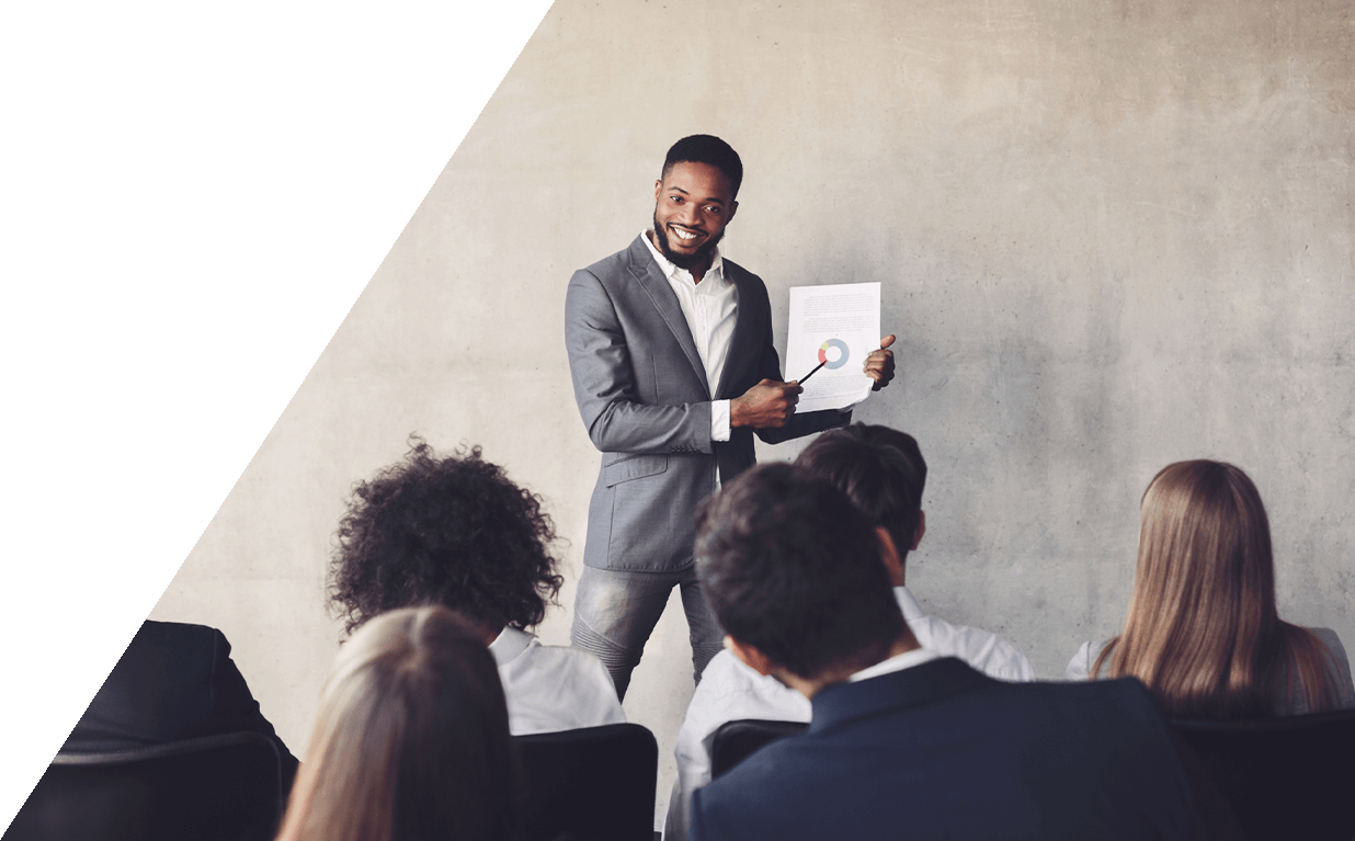 Man in a suit presenting a report to an audience in a professional setting.