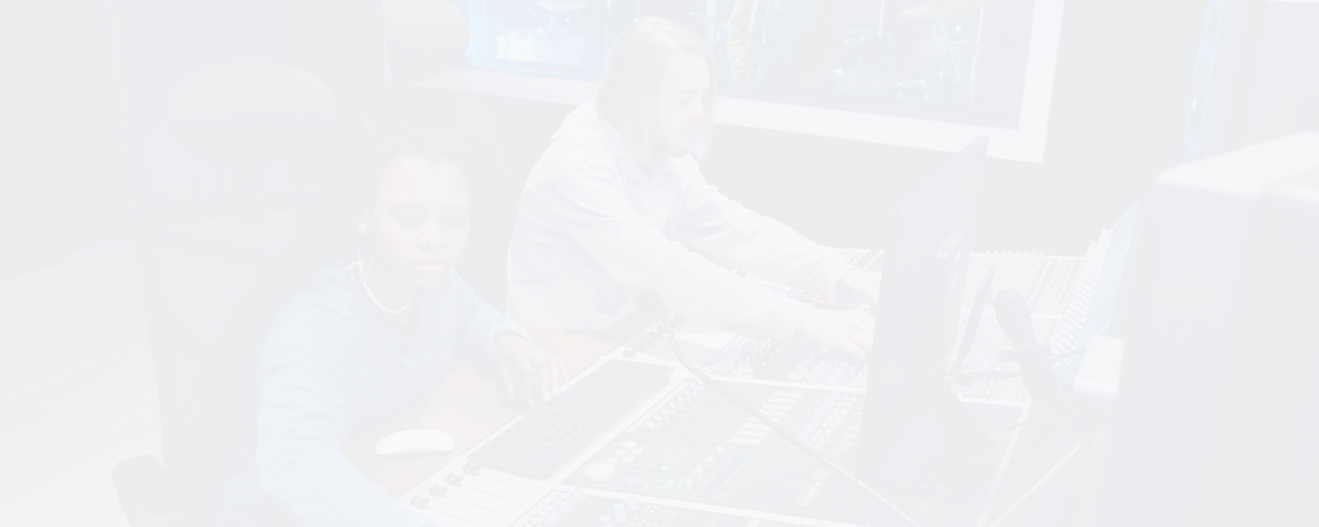 Two individuals working at a sound mixing console in a studio environment.